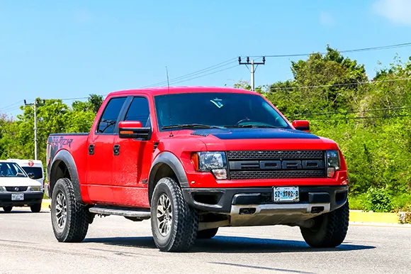 A red Ford Lobo Raptor is being driven on the road.