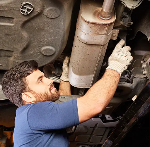 An expert car mechanic performing an emission test by checking a suspended car's exhaust