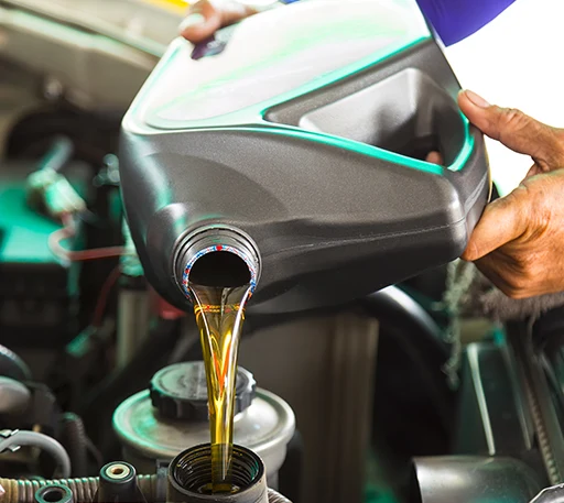 A car mechanic performing an oil change by pouring in new car engine oil
