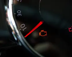 A car dashboard displaying the check engine light