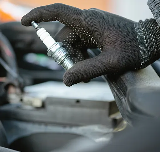 An auto electrician holding up a brand-new spark plug