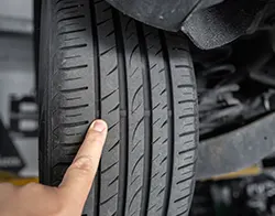 A mechanic pointing out the wear on a car's tire