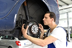 A mechanic working on braking system repairs on the lifting platform